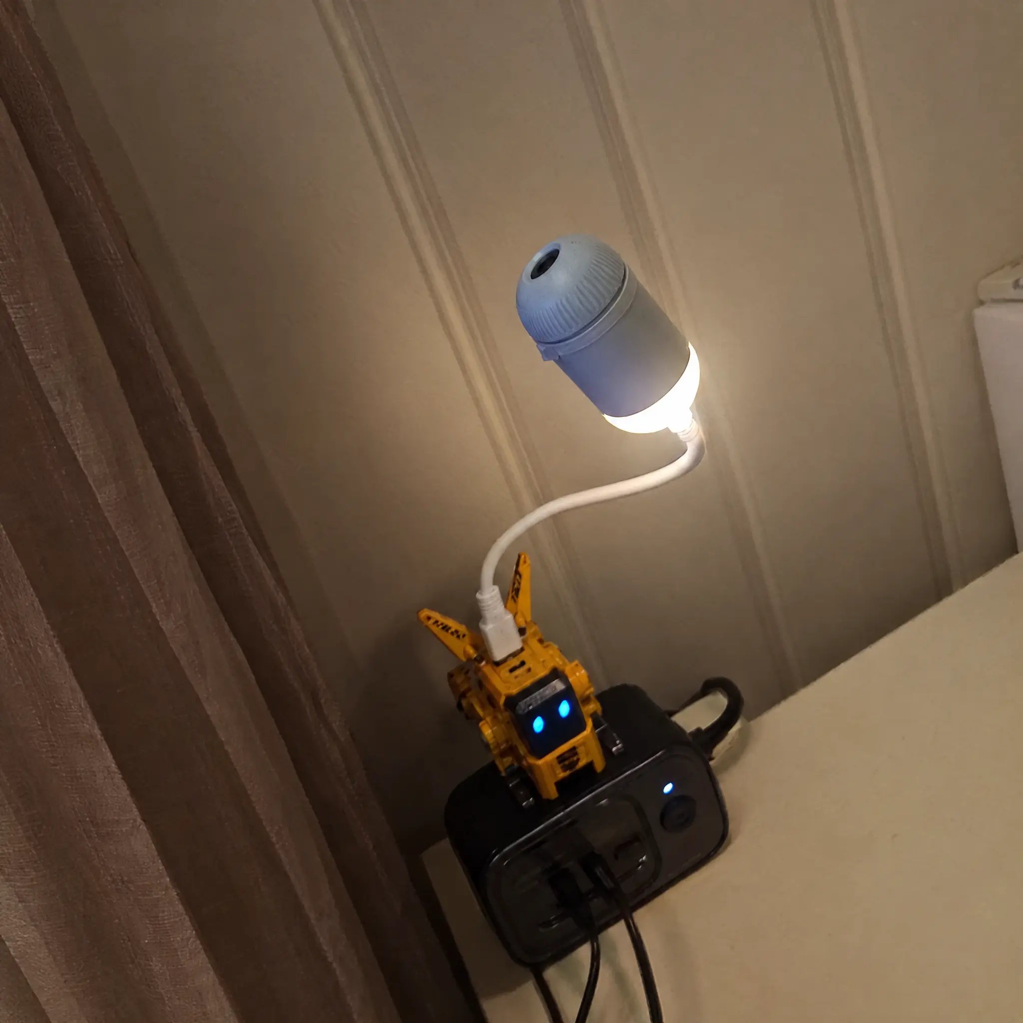 Projector plugged into a wall socket at night, glowing warm